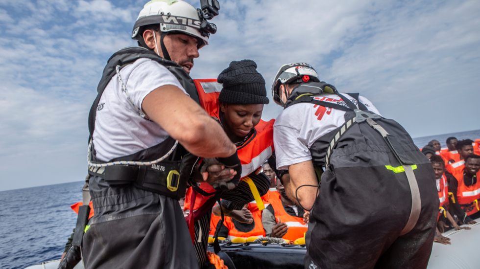 Einer Frau wird in ein Rettungsboot geholfen