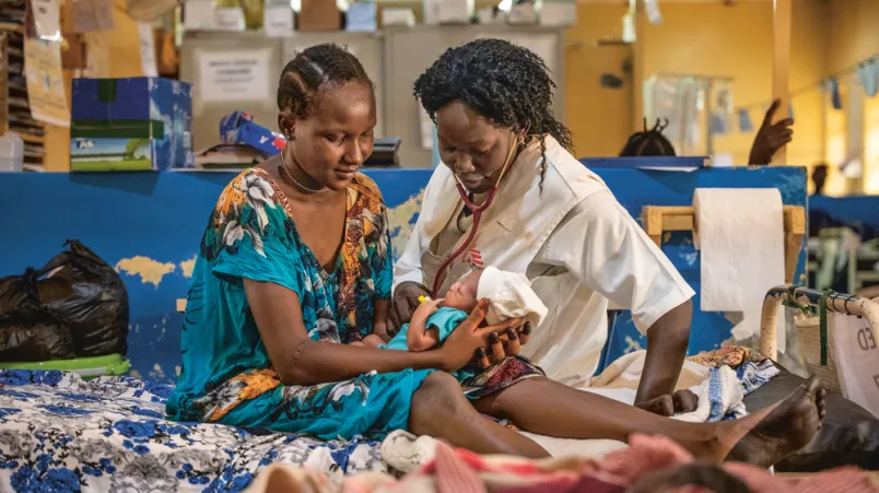 Mitarbeiterin und Mutter blicken auf Säugling