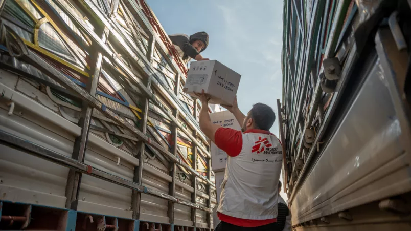 Mitarbeitender zwischen Lastwagen mit Hilfsgütern