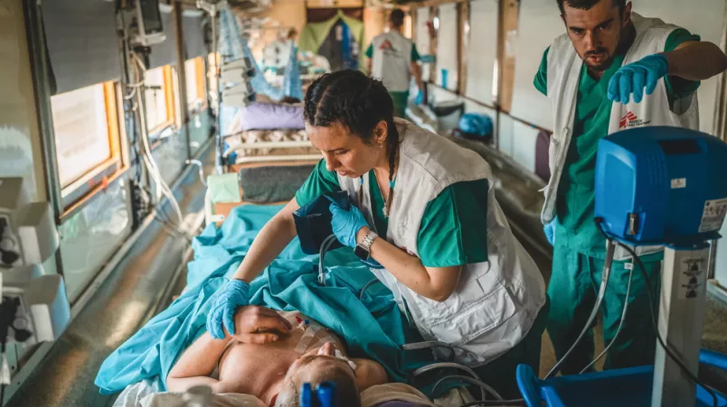 Zwei Mitarbeitende arbeiten an Bett von Patient in Zug