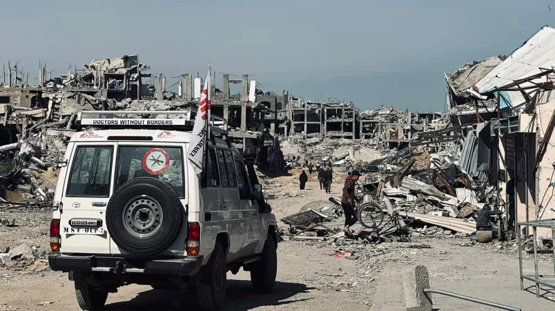 Geländewagen mit Ärzte ohne Grenzen Logo vor zerstörten Gebäuden