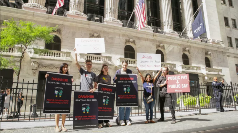 Aktivist*innen mit Plakaten: Cepheid soll Preis für GeneXpert-Tests für Tuberkulose senken