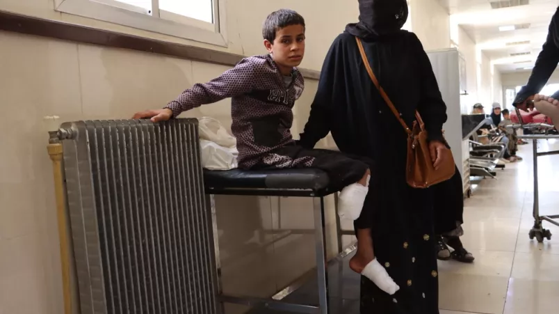 Abdulrazzaq sitzt auf einer Liege im Krankenhaus und hat einen Verband um seinen rechten Beinstumpf und linken Fuß.