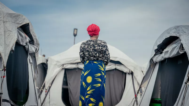 Frau steht vor Zelten mit Rücken zur Kamera