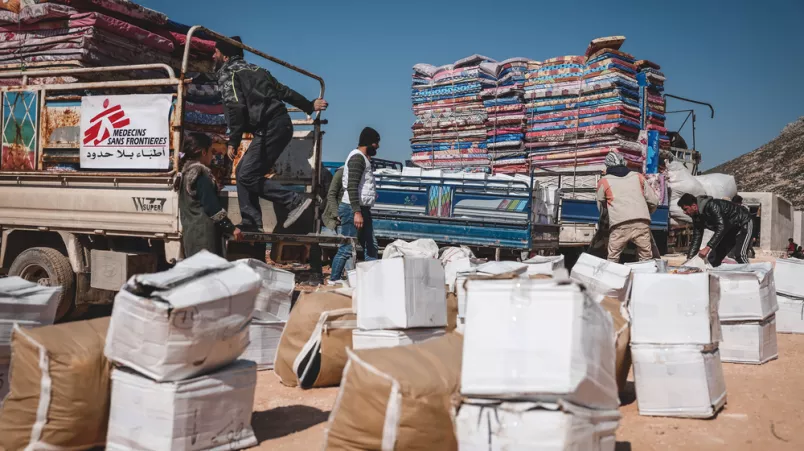 Aus mehreren LKW laden unsere Mitarbeitenden und Helfer*innen Hilfsgüter und Matratzen aus und sortieren die Pakete.