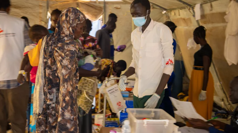 Patient*innen erhalten medizinische Versorgung in einem Behandlungszelt.