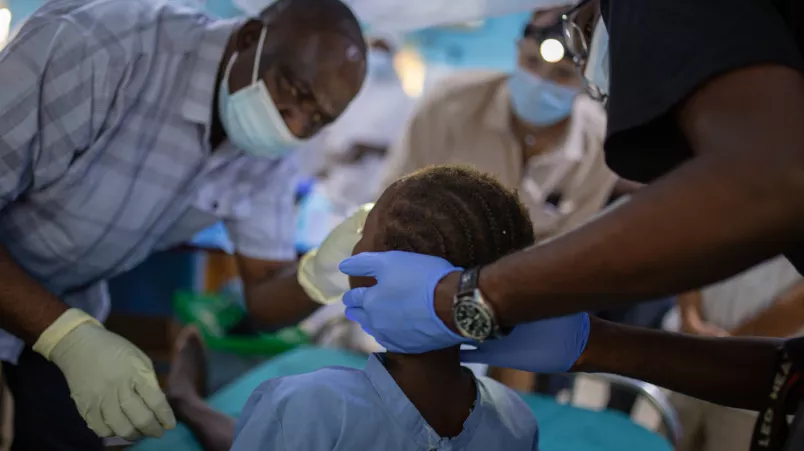 Mitarbeitende untersuchen das Gesicht eines Kindes