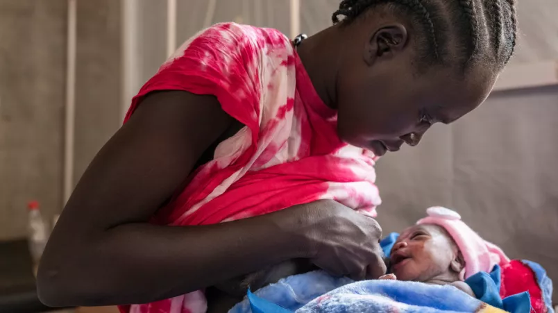 Frau gibt Neugeborenem die Brust