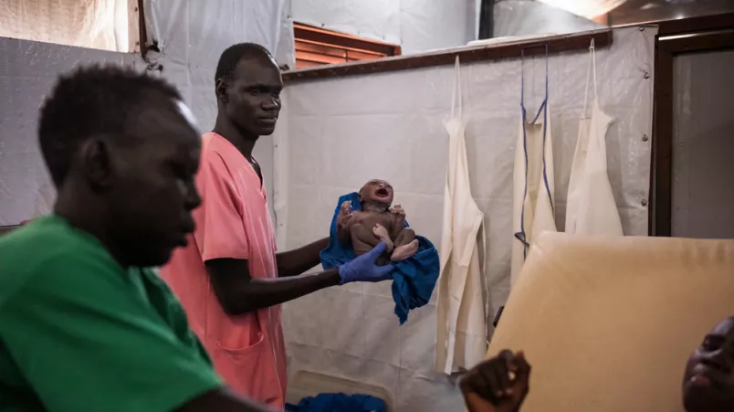 Mitarbeitende untersuchen Neugeborenes