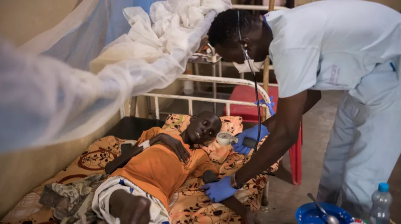 Mitarbeiter misst Blutdruck von Mann in Krankenbett