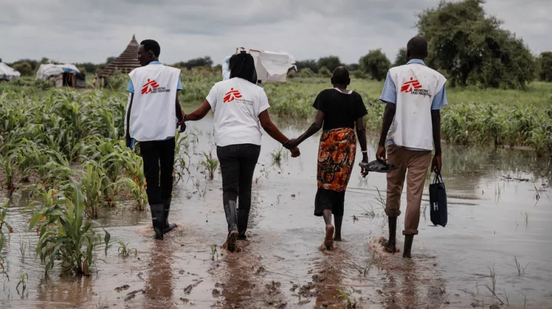 4 Personen laufen durch überschwemmte Gebiete, Südsudan