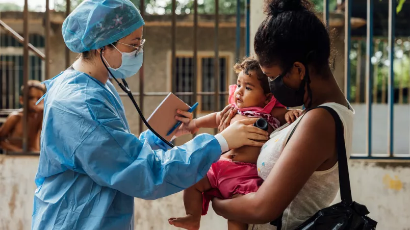 Eine unserer Mitarbeiterinnen hört ein Kind mit einem Stethoskop ab.