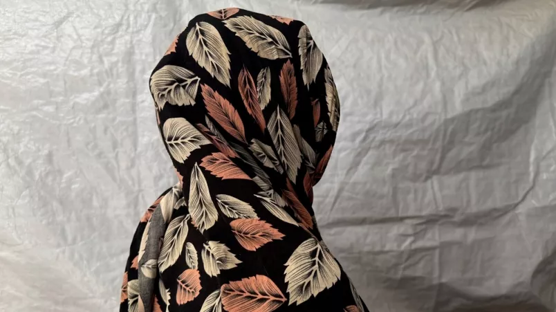 Eine Frau mit gemustertem Kopftuch steht in einem Zelt in einem Vertriebenencamp in Sudan.