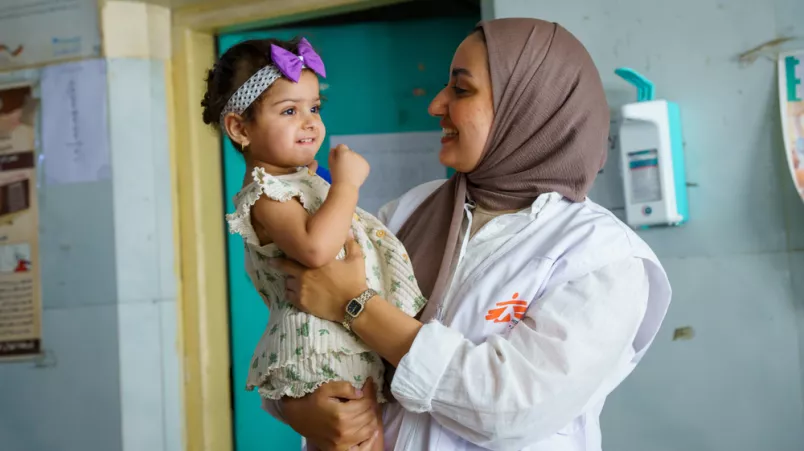 Mitarbeiterin hält kleines Mädchen auf Arm