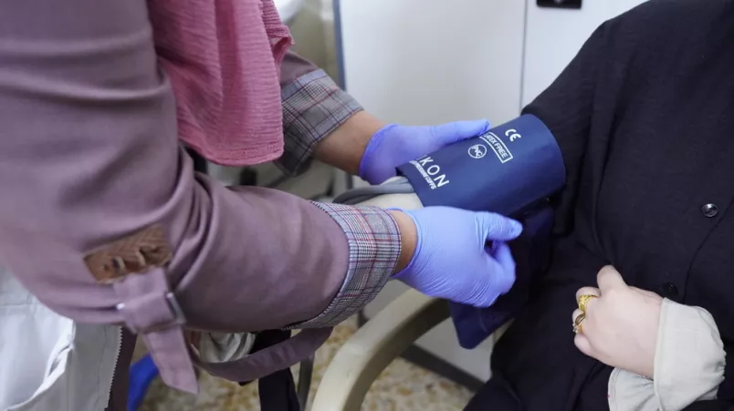 Hand legt Blutdruckmanschette um Arm von Frau