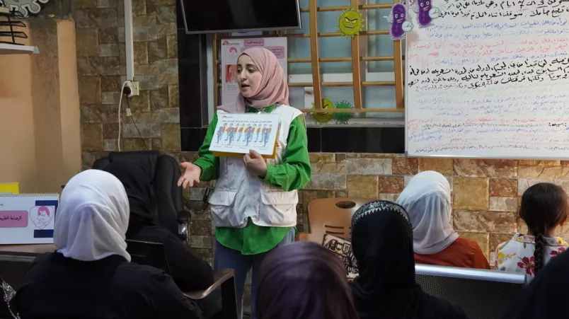 Mitarbeitende mit Grafik zeigt Grafik und spricht zu sitzenden Frauen