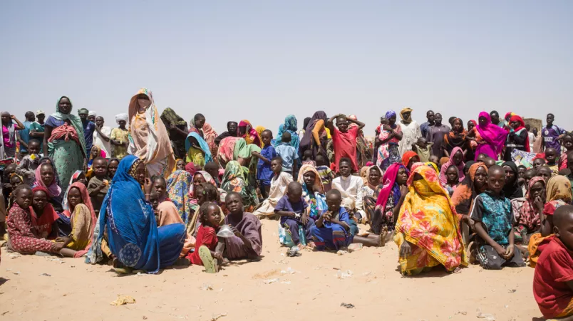 Gruppe Menschen sitzt auf nicht befestigtem Boden