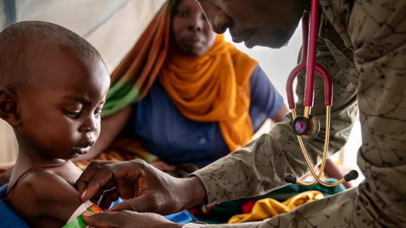 Mitarbeiter misst Armumfang von Kleinkind