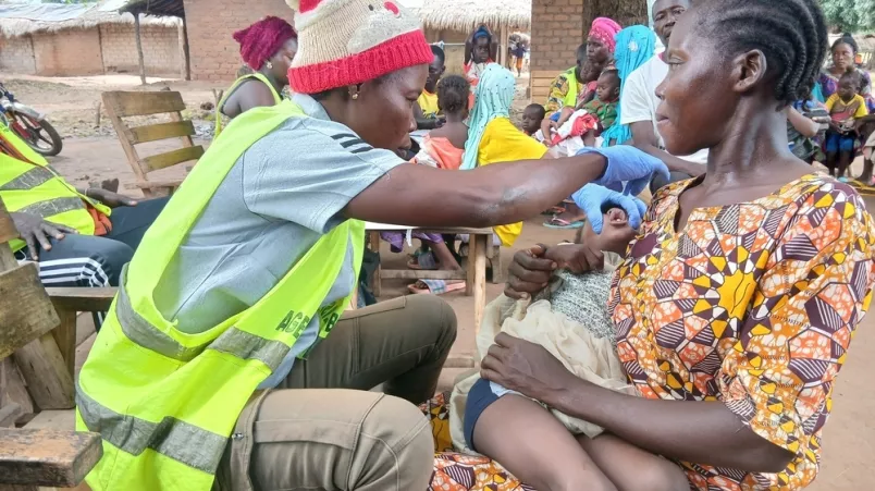 Kleines Kind auf Schoß von Mutter bekommt Schluckimpfung