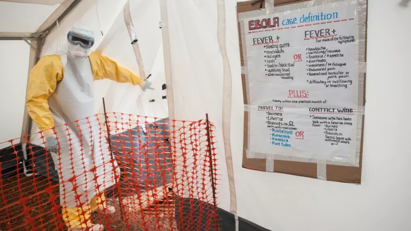 Arzt in Schutzausrüstung vor Eingang zur Hochrisikozone eines Ebola-Behandlungszentrums