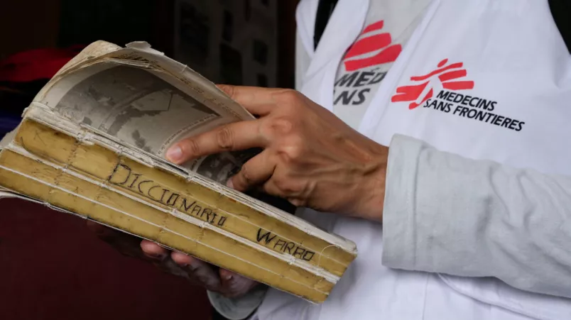 Ein Mitarbeiter mit Ärzte ohne Grenzen-Weste liest einen altes Wararo-Wörterbuch.