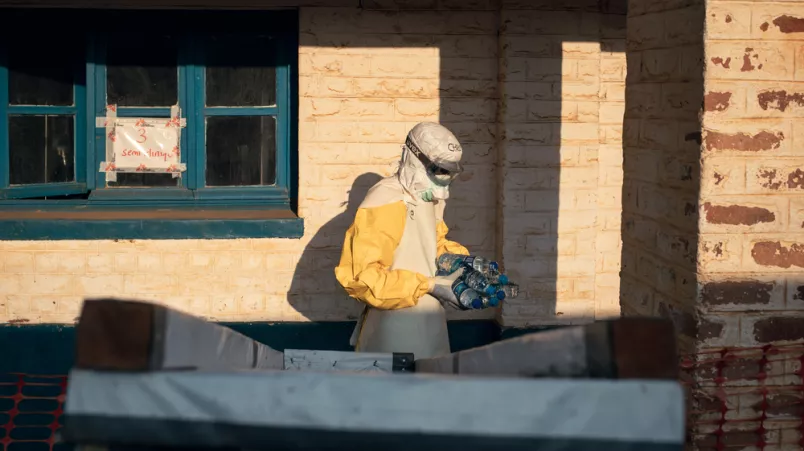 Ein Mensch in Schutzkleidung trägt Wasserflaschen auf dem Arm
