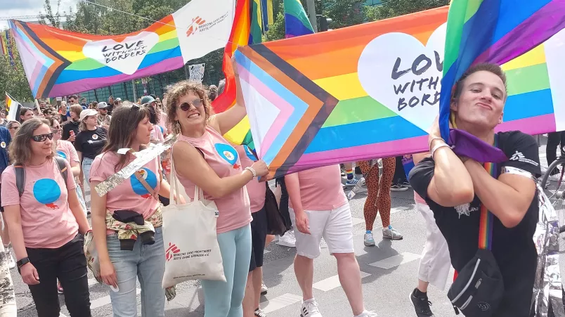 Mitarbeitende von Ärzte ohne Grenzen mit Regenbogen-Fahnen.