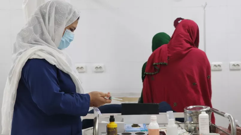 Eine medizinische Mitarbeiterin bereitet eine Spritze für die Behandlung einer Patientin vor.