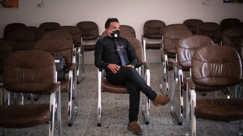 Ein Mann mit Maske sitzt auf einem Stuhl