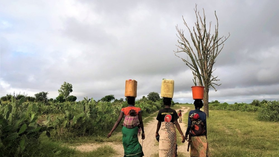 Drei Frauen tragen schwere Wasserkanister auf ihrem Kopf, einen langen Weg zurück in ihr Dorf