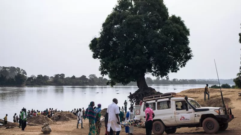 Flussufer wo ein Ärzte ohne Grenzen Auto wartet. Die Tragbahre mit der Patientin wird zum Auto getragen.