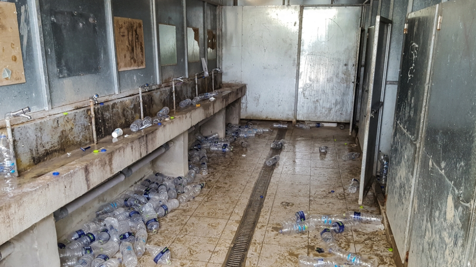 Ein verschmutzes Badezimmer mit vielen leeren Plastikflaschen auf dem Boden
