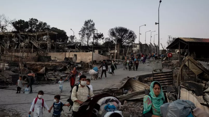 Eine Kolonne von Frauen, Männern und Kindern, die mit Einkaufswagen aus dem Geflüchtetencamp Moria fliehen