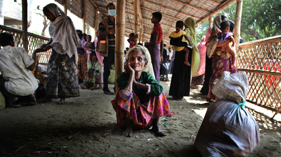 Eine ältere Frau sitzt nach ihrer Flucht aus Myanmar am Boden.