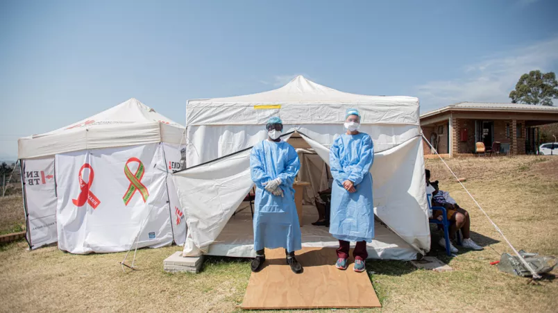 An verschiedenen Punkten außerhalb der Kliniken erhalten die Ankommenden Informationen und werden auf Symptome von Covid-19 untersucht.