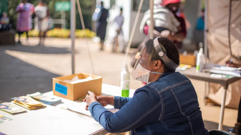 An verschiedenen Punkten außerhalb der Kliniken erhalten die Ankommenden Informationen und werden auf Symptome von Covid-19 untersucht.
