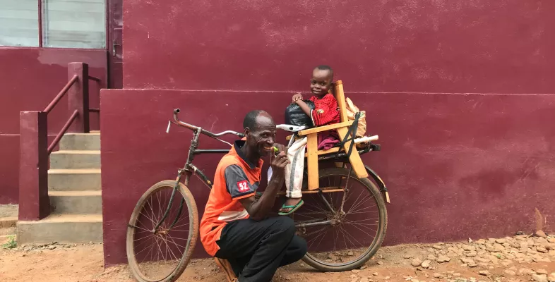 Der 8-jährige Dieu-Beni und sein Vater auf einem Fahrrad.