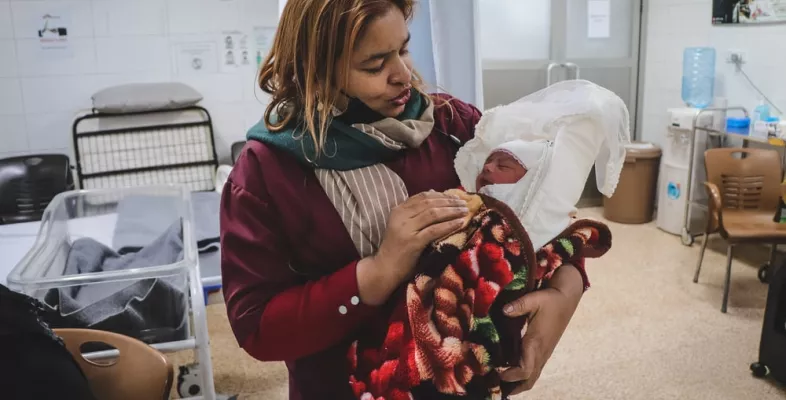 Eine unserer Hebammen hält ein Neugeborenes im Arm.