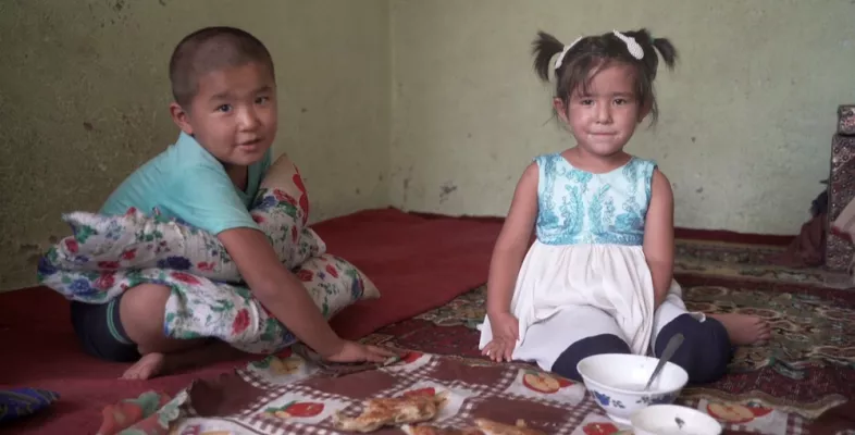 Ein Junge und ein Mädchen sitzen auf dem Boden ihres Wohnhauses.