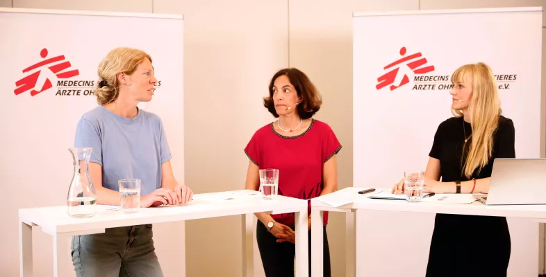 Drei Frauen stehen an Präsentationstischen und sprechen über ihre Forschung und Arbeit.