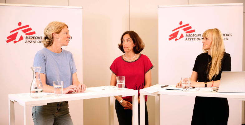 ThemenTalk Hero Drei Frauen stehen an Präsentationstischen und sprechen über ihre Forschung und Arbeit.