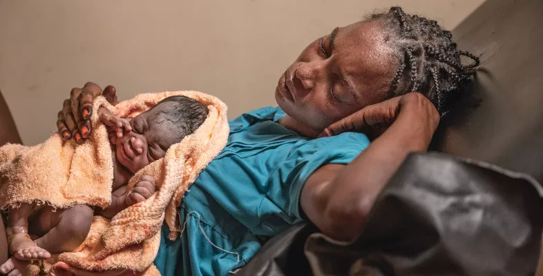 Eine erschöpfte Mutter mit ihrem Neugeborenen