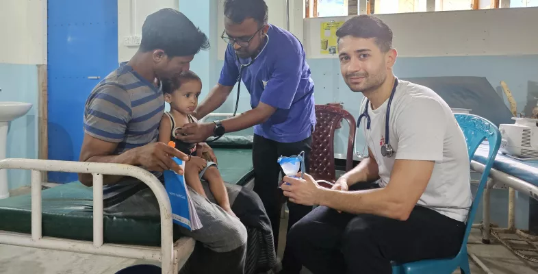 Junge sitzt auf dem Schoß seines Vaters während unsere Ärzte ihn behandeln.