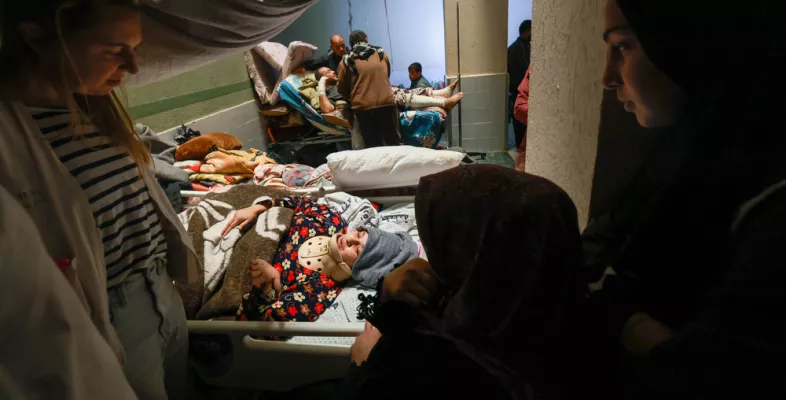 Behandelnde und Angehörige am Bett einer Patientin.