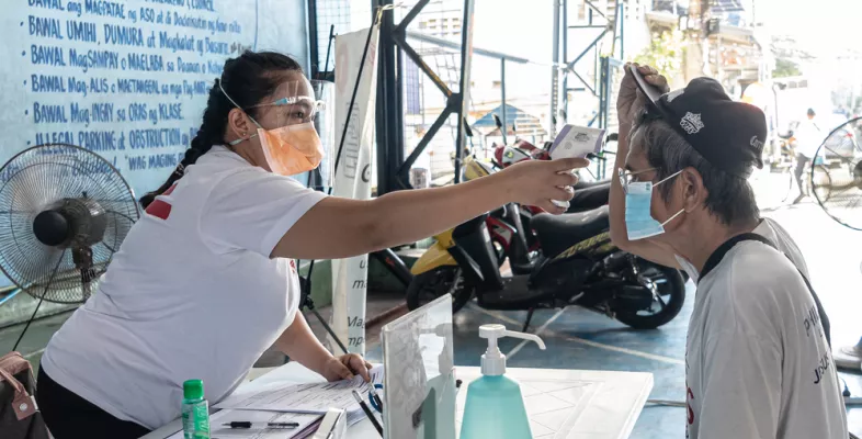 Mitarbeitende misst Temperatur von TB-Patient.