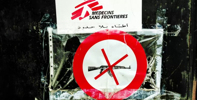 Ein Piktogramm mit einem durchgestrichenen Gewehr und einem Ärzte ohne Grenzen Schild