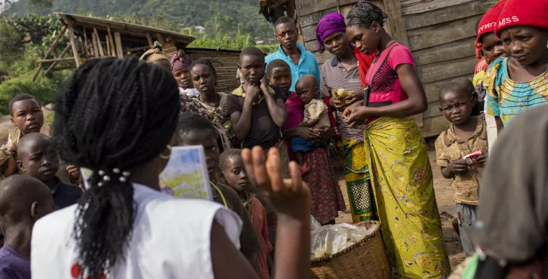 Unser Health-Promotion-Team in Masisi, D.R. Kongo, erklärt auf Märkten und in Vertriebenencamps über Gesundheitsthemen auf und über unser kostenloses medizinisches Angebot. Gesundheitsberaterin spricht vor einer Gruppe Menschen