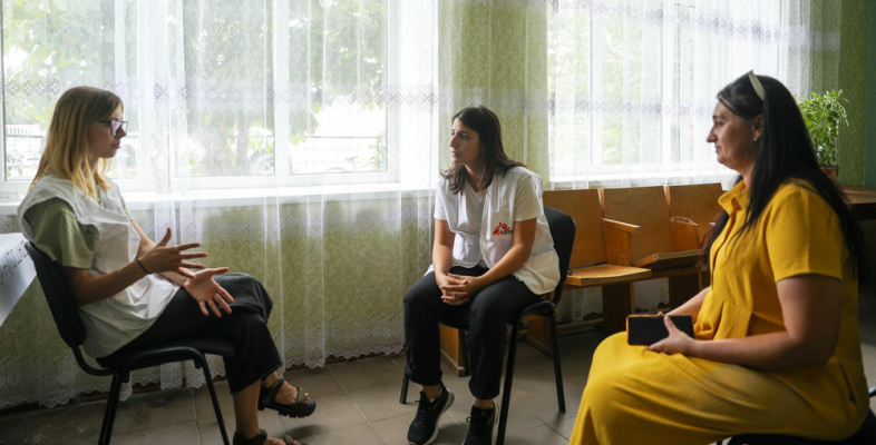 Mit mobilen Teams bieten wir vor Ort in betroffenen Regionen der Ukraine Hilfe an. Drei Frauen in Stuhlkreis im Gespräch miteinander, eine ist Projektkoordinatorin