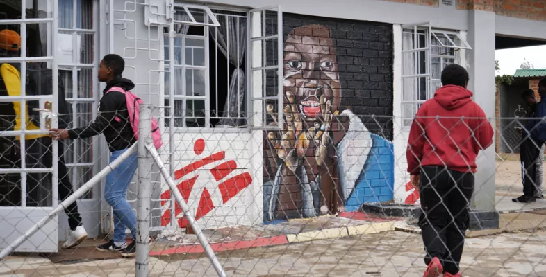 Jugendliche betreten ein Haus mit bemalter Wand