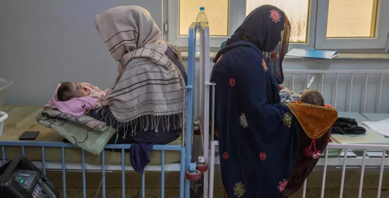 Zwei Frauen sitzen mit ihren Babys auf dem Schoss auf Betten